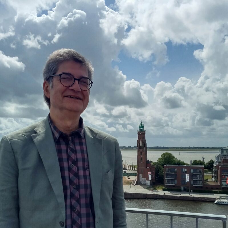 Thomas Kühn auf dem Dach des Timeport 3 in Bremerhaven mit dem Hermann-Loschen-Turm und der Weser im Hintergrund.